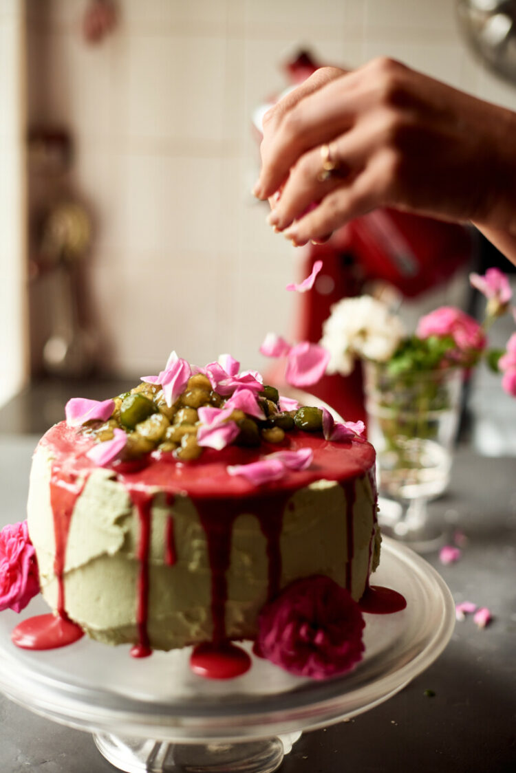 Sprinkling decorative roses on matcha and raspberry boba tea cake
