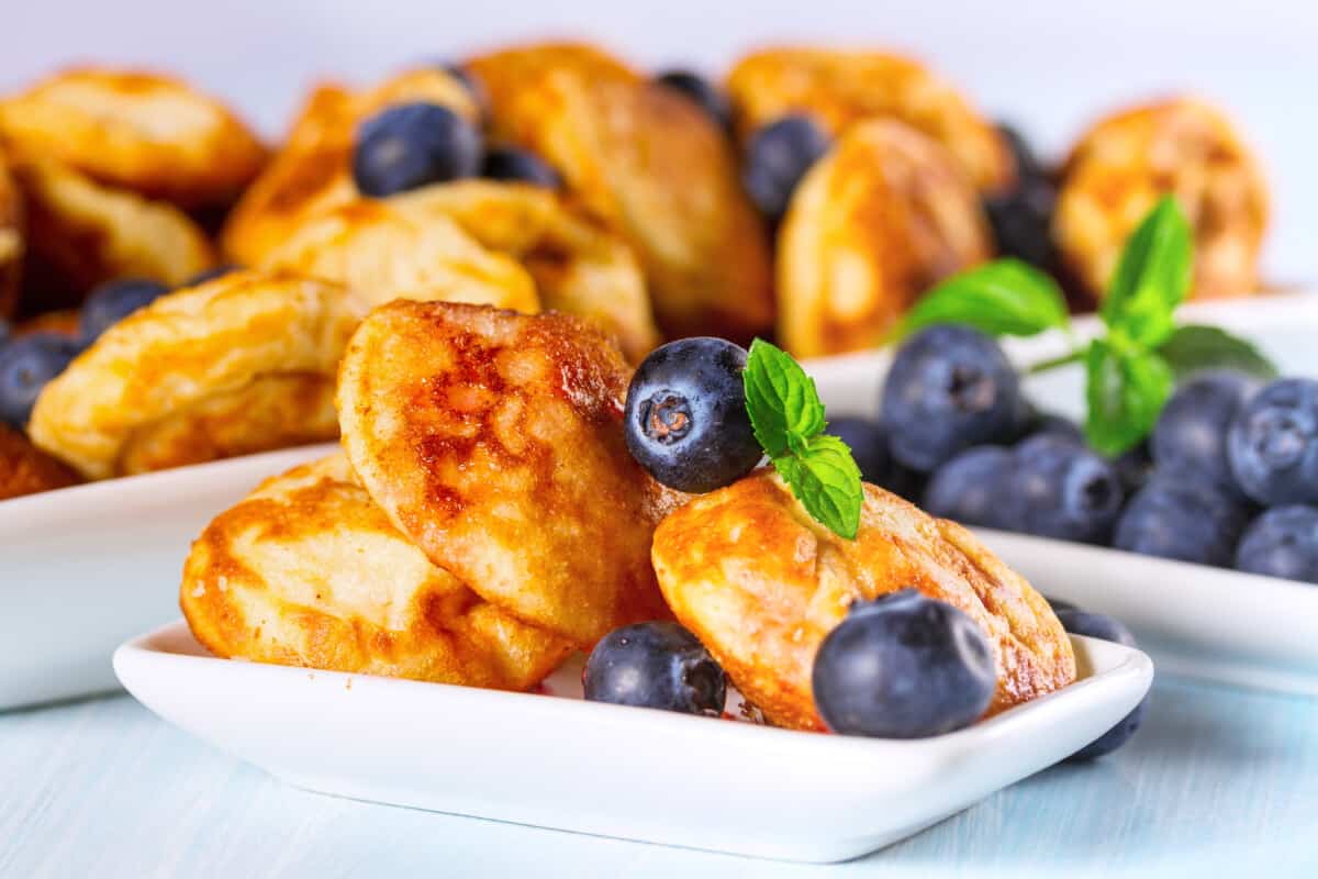 Mini pancakes on small rectangular plates with blueberries on top