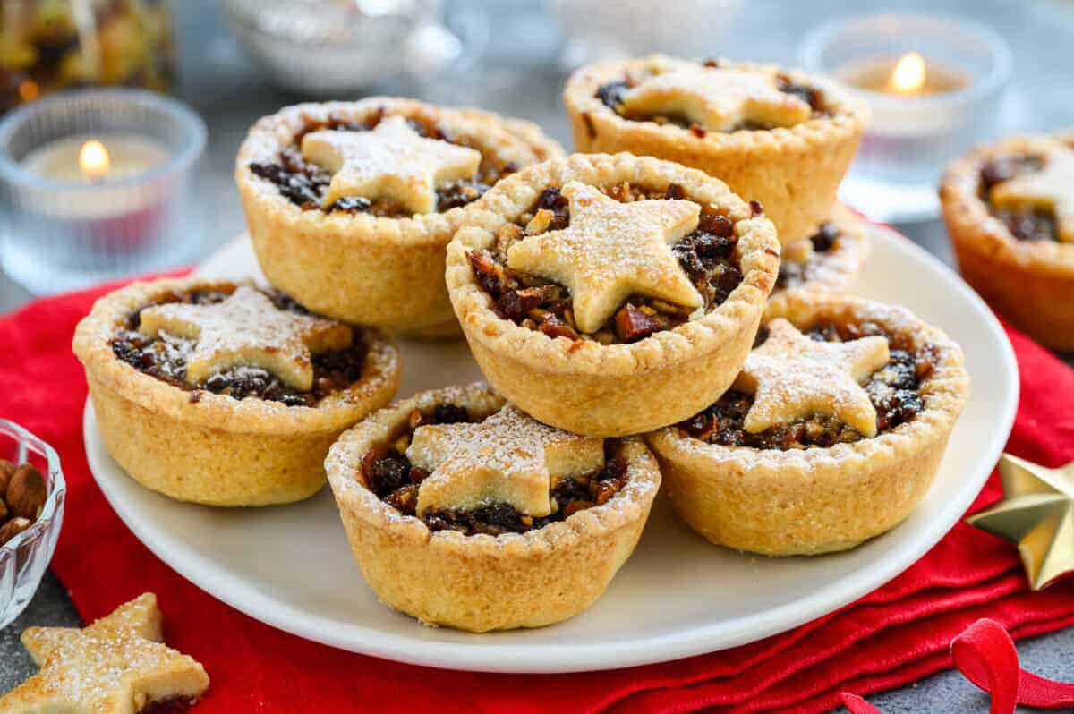 Multiple Christmas mince pies with a star design on top arranged on a plate